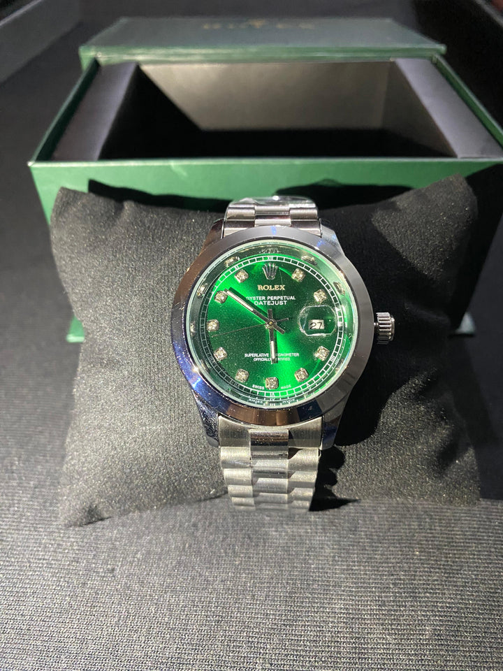 Rolex watch with green face and silver bracelet on a gray surface